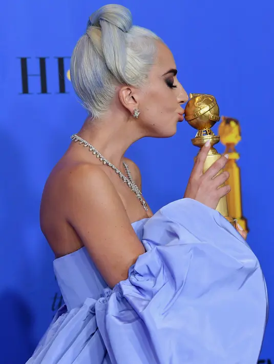 Lady Gaga mencium piala penghargaan Golden Globes 2019 di The Beverly Hilton, California, Minggu (6/1). Lagu Lady Gaga berjudul 'Shallow' memenangkan Golden Globes 2019 kategori lagu orisinal terbaik. (KEVIN WINTER/GETTY IMAGES NORTH AMERICA/AFP)