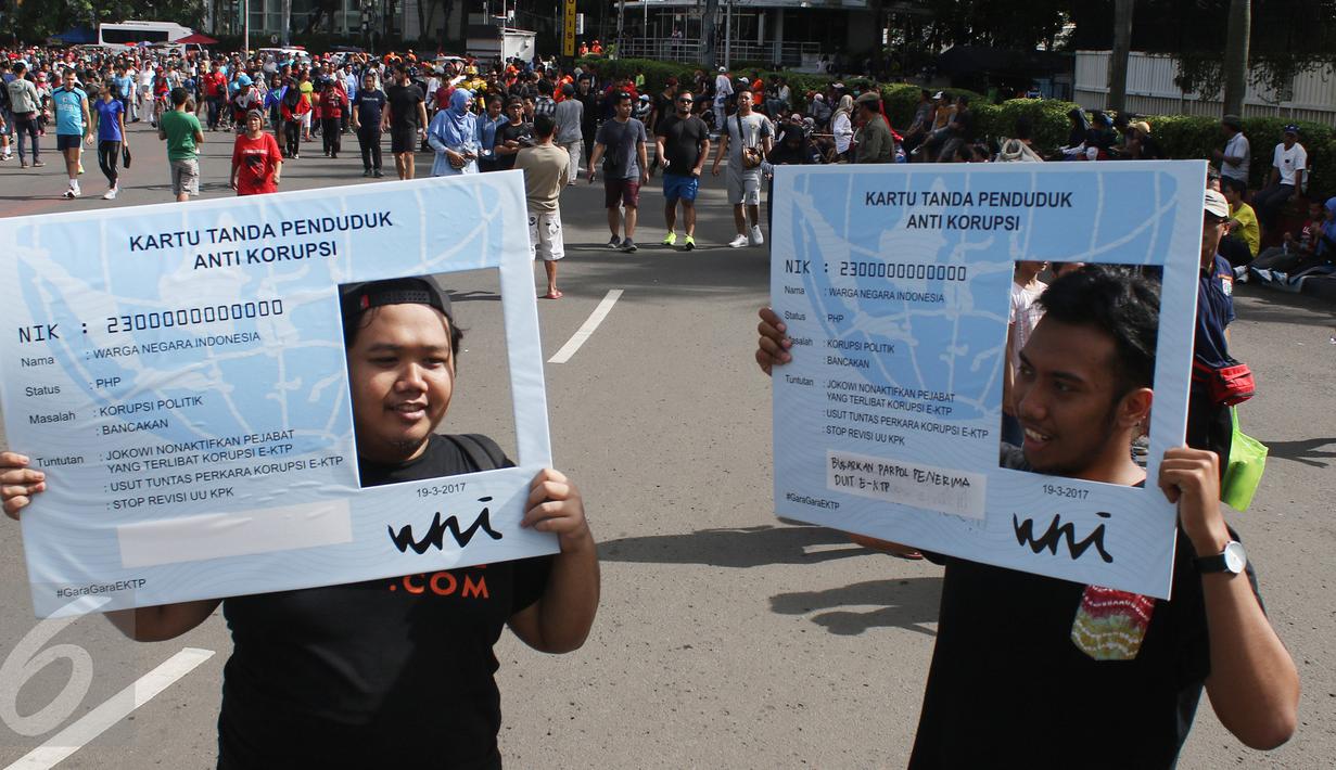 Dua orang pria berpose dengan papan mirip E-KTP di CFD, Jakarta, Minggu (19/3). Aktivis Gerakan Sapu Koruptor menuntut penegak hukum untuk segera menuntaskan kasus korupsi E-KTP. (Liputan6.com/Angga Yuniar) 