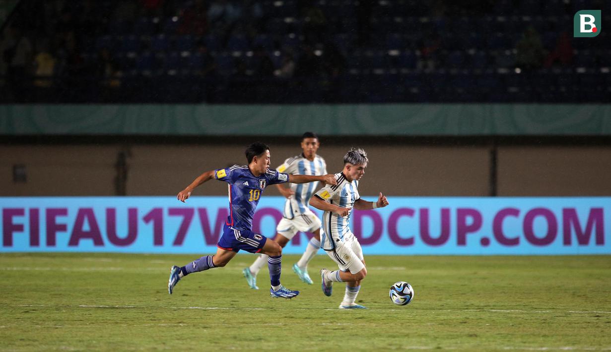<p>Pemain Timnas Argentina U-17, Santiago Lopez (kanan) menggiring bola dikejar pemain Timnas Jepang U-17, Ryonosuke Sato pada laga kedua Grup D Piala Dunia U-17 2023 di Stadion Si Jalak Harupat, Kabupaten Bandung, Selasa (14/11/2023). (Bola.com/Ikhwan Yanuar)</p>