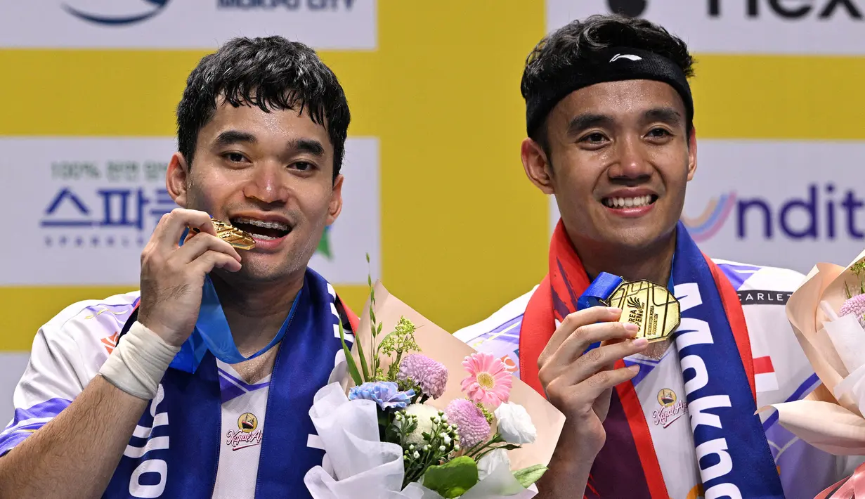 Ganda putra Indonesia, Leo Rolly Carnando (kiri) dan Bagas Maulana merayakan kemenangan di podium setelah pertandingan final bulu tangkis ganda putra Korea Open di Mokpo Indoor Stadium, Minggu 1 September 2024. (ANTHONY WALLACE/AFP)