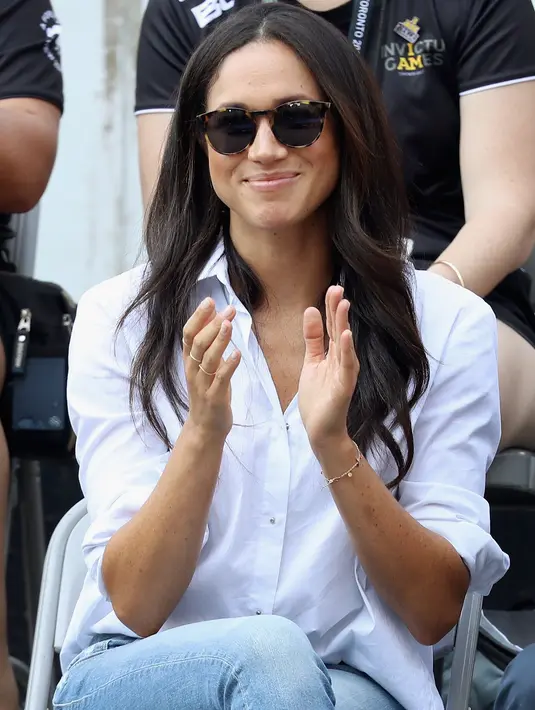 Kekasih Pangeran Harry yang juga aktris, Meghan Markle menonton pertandingan tenis kursi roda selama Invictus Games 2017 di Toronto, Kanada, Senin (25/9). Meghan tampil lebih kasual dengan kemeja putih dan jeans skinny. (Chris Jackson/GETTY IMAGES/AFP)