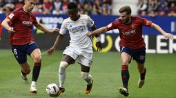 Pemain Real Madrid, Vinicius Junior, berebut bola dengan pemain Osasuna, Lucas Torro dan Jon Moncayola, pada laga pekan ke-29 La Liga 2023/2024 di Stadion El Sadar, Sabtu (16/03/2024). Vinicius Junior tampil gemilang dengan memborong dua gol. (AP Photo/Alvaro Barrientos)