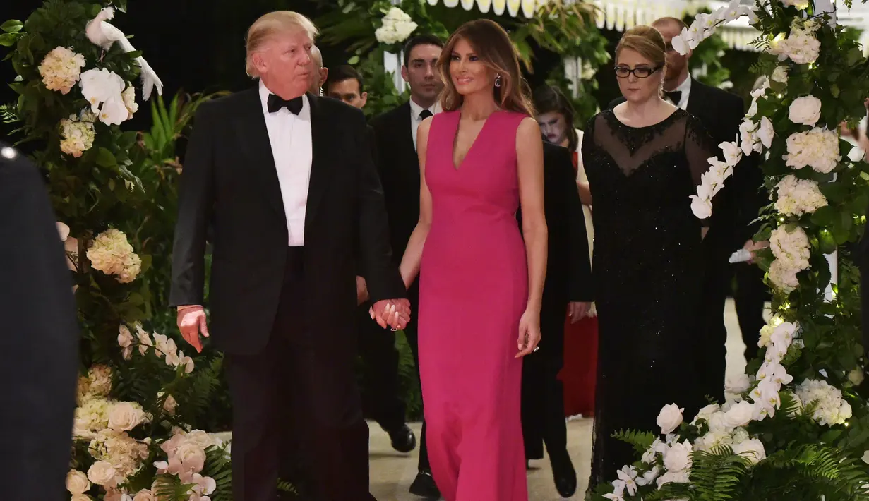Melania Trump mendampingi Donald Trump saat menghadiri gala tahunan Palang Merah Amerika ke-60 di Mar-a-Lago, Florida, AS (4/2). First Lady Melania Trump tampil anggun dengan mengenakan gaun berwarna merah muda. (AFP/Mandel Ngan)