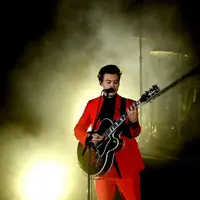 Sejumlah  penggemar mengulurkan tangan untuk bersalaman dengan sang idola, namun sayangnya, salah satu fansnya justru berbuat hal yang kelewatan. Ia meremas bagian vital Harry Styles. (AFP/Kevin Winter)