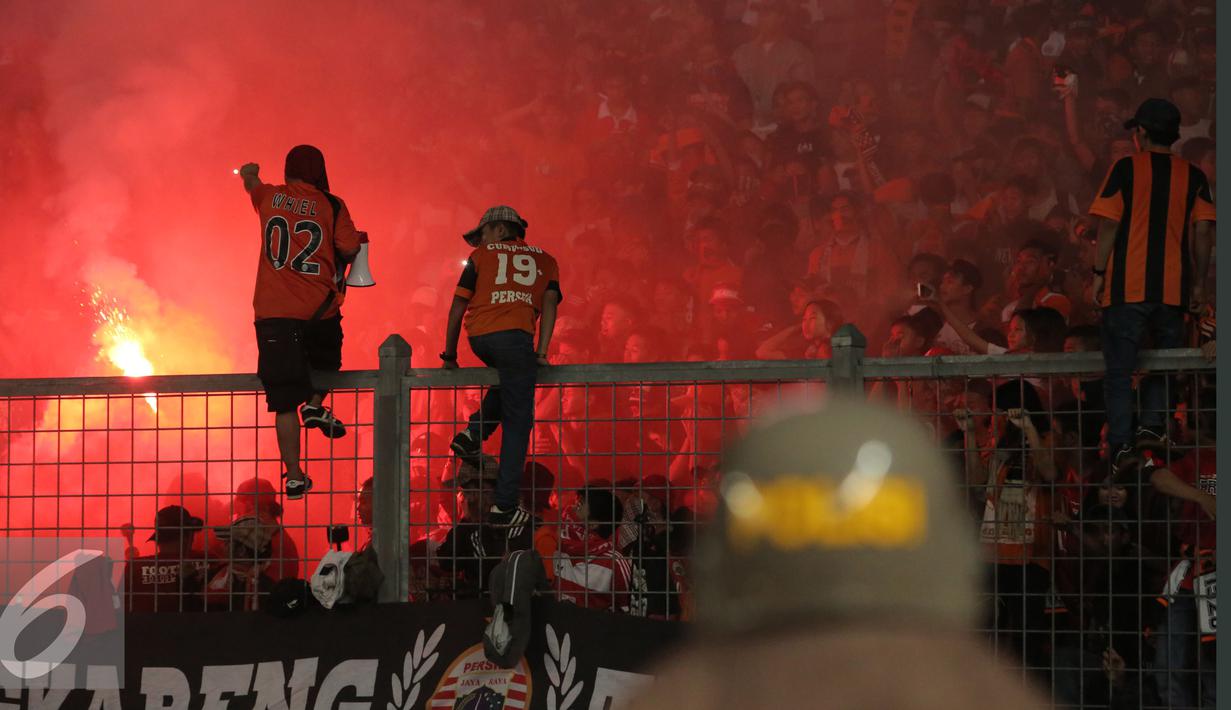 Suporter menyalakan flare saat menyaksikan laga Persija melawan Sriwijaya FC pada lanjutan Torabika Soccer Championship presented by IM3 Ooredoo di Stadion GBK Jakarta, Jumat (24/6).Laga dihentikan di menit 81. (Liputan6.com/Helmi Fithriansyah)