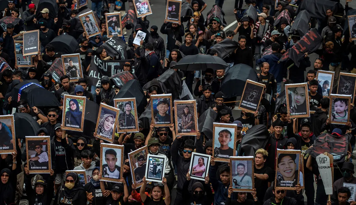 Pendukung sepak bola mengikuti aksi unjuk rasa memperingati 40 hari Tragedi Kanjuruhan, di depan balai kota Malang, Jawa Timur, Kamis (10/11/2022). Mereka membawa sejumlah keranda jenazah dengan foto-foto korban tragedi Kanjuruhan, dan poster berisi tuntutan. (JUNI KRISWANTO / AFP)