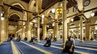 Umat Muslim melaksanakan salat tarawih dengan menerapkan jaga jarak selama bulan Ramadan di Masjid al-Azhar, Kairo, Minggu (17/5/2020). Bagi umat Islam di seluruh dunia menjalankan ibadah puasa tahun ini di tengah pembatasan akibat corona Covid-19 adalah yang pertama kalinya. (Samer ABDALLAH/AFP)