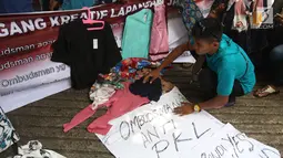 Pedagang kaki lima (PKL) dari Forum Pedagang Kreatif Lapangan Jatibaru menggelar dagangan mereka di depan kantor Ombudsman, Jakarta, Selasa (3/4). Aksi ini untuk mempertanyakan laporan Ombudsman mengenai penataan Tanah Abang. (Liputan6.com/Arya Manggala)