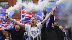 Para fans Glasgow Rangers menyalakan granat asap di luar Ibrox Stadium (7/3/2021) untuk merayakan keberhasilan tim kesayangan mereka merebut gelar Liga Utama Skotlandia setelah memimpin 20 poin dari saingan terdekat, Glasgow Celtic. (AFP/Andy Buchanan)