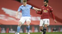 Gelandang Manchester City Kevin De Bruyne (kiri) bersaing dengan gelandang Manchester United Bruno Fernandes pada leg pertama semifinal Piala Liga Inggris di Old Trafford pada 6 Januari 2021. (PETER POWELL / KOLAM RENANG / AFP)