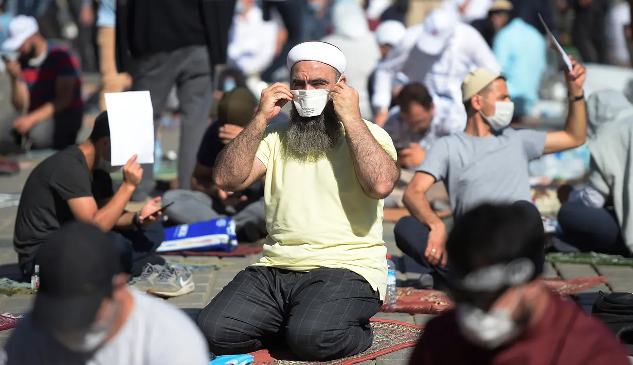 Jemaah mengenakan masker untuk menghindari penyebaran COVID-19 saat menunggu di distrik bersejarah Sultanahmet, dekat Hagia Sophia, Istanbul, Turki, Jumat (24/7/2020). Umat muslim melaksanakan salat Jumat pertama di Hagia Sophia dalam 86 tahun terakhir. (AP Photo/Yasin Akgul)