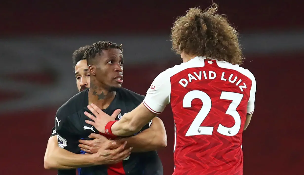 Striker Crystal Palace, Wilfried Zaha (kiri) dan bek Arsenal, David Luiz terlibat pertikaian dalam laga lanjutan Liga Inggris 2020/21 di Emirates Stadium, Kamis (14/1/2021). Crystal Palace bermain imbang 0-0 dengan Arsenal. (AFP/Julian Finney/Pool)