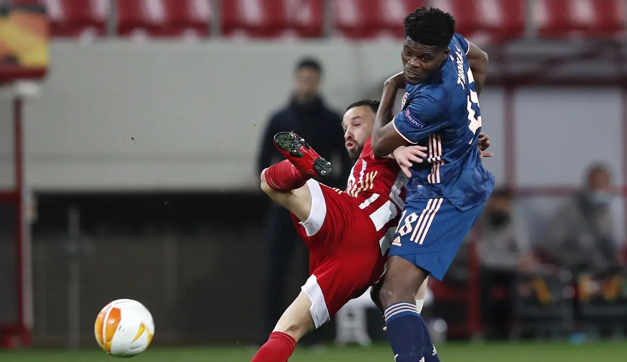 Gelandang Arsenal, Thomas Partey (kanan) berebut bola dengan gelandang Olympiakos, Mathieu Valbuena dalam laga leg pertama babak 16 besar Liga Europa 2020/2021 di Georgios Karaiskakis Stadium, Kamis (11/3/2021). Arsenal menang 3-1 atas Olympiakos. (AP/Thanassis Stavrakis)