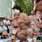 Dua orang bayi menangis saat digendong pegulat sumo dalam Lomba Bayi Menangis di kuil Irugi, Jepang, (21/9/14). (AFP PHOTO/ Yoshikazu TSUNO)