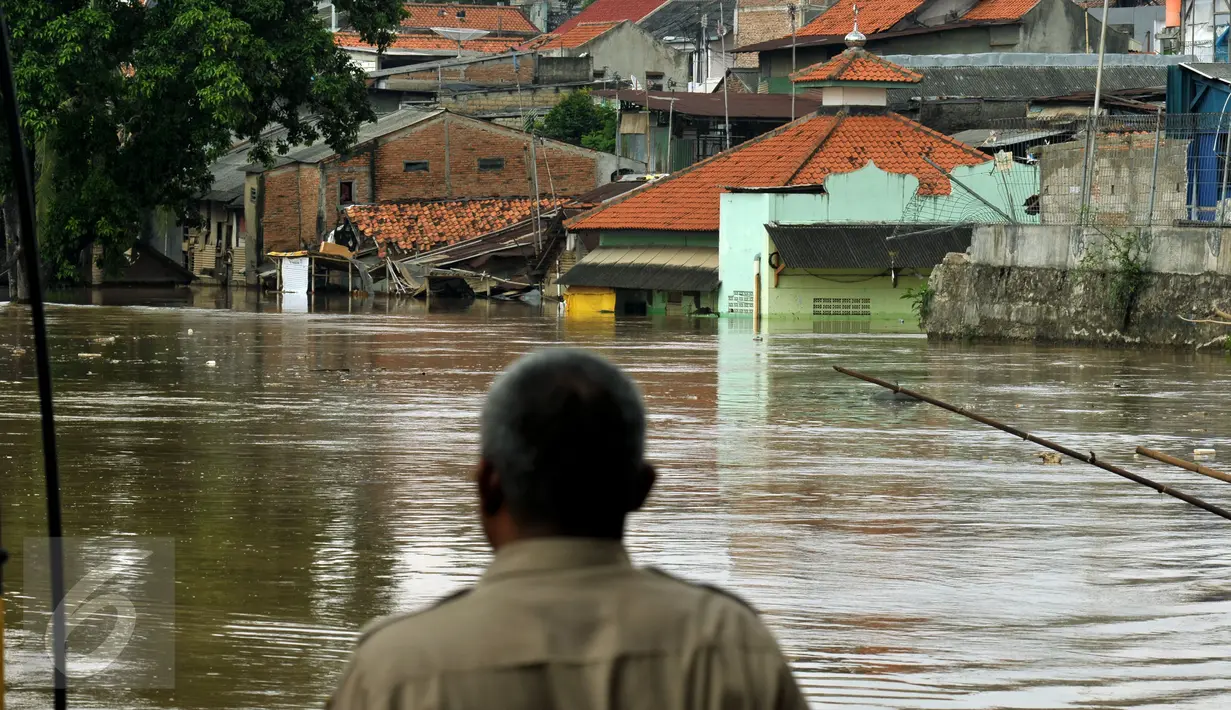 Warga menyaksikan luapan air kali Ciliwung yang menggenangi pemukiman di kawasan Rawajati, Jakarta, Selasa (8/3/2016). Akibat banjir kiriman dari Bogor, ratusan rumah di kawasan Rawajati terendam hingga kedalaman 120cm. (Liputan6.com/Helmi Fithriansyah)