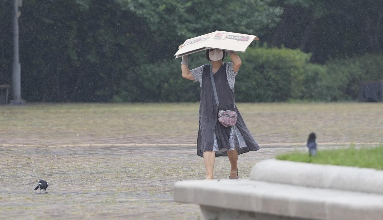 Seorang wanita mengenakan masker untuk membantu mengekang penyebaran virus corona berjalan di tengah hujan di Seoul, Korea Selatan, Selasa (31/8/2021). Korea Selatan pada hari Rabu melaporkan lebih dari 2.000 kasus virus corona baru. (AP Photo/Lee Jin-man)