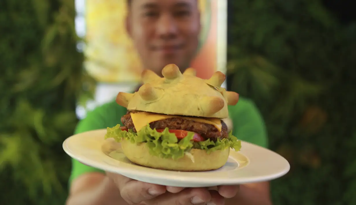 Pemilik restoran Hoang Tung menunjukkan burger berbentuk virus corona COVID-19 di Hanoi, Vietnam, Rabu (25/3/2020). Sebuah restoran di Hanoi membuat kreasi baru mereka yang disebut ‘Burger Corona’. (AP Photo/Hau Dinh)