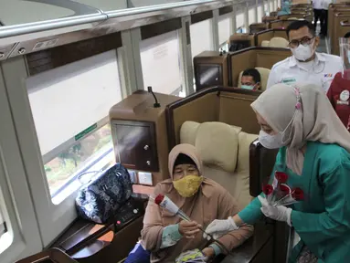 Petugas PT KAI Daop 1 Jakarta membagikan bunga kepada penumpang di Stasiun Gambir, Rabu (21/4/2021). PT KAI DAOP 1 memperingati Hari Kartini menginspirasi para penumpang agar semangat berjuang melawan pandemi COVID-19 dengan selalu menerapkan protokol kesehatan. (Liputan6.com/Herman Zakharia)