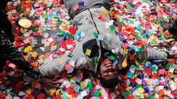 Seorang pria berbaring diantara confetti saat perayaan tahun baru di Times Square, New York, AS (1/1). Pesta pergantian tahun di New York dipusatkan di Times Square, ribuan orang membanjiri tempat tersebut untuk merayakannya. (Reuters/Stephanie Keith)