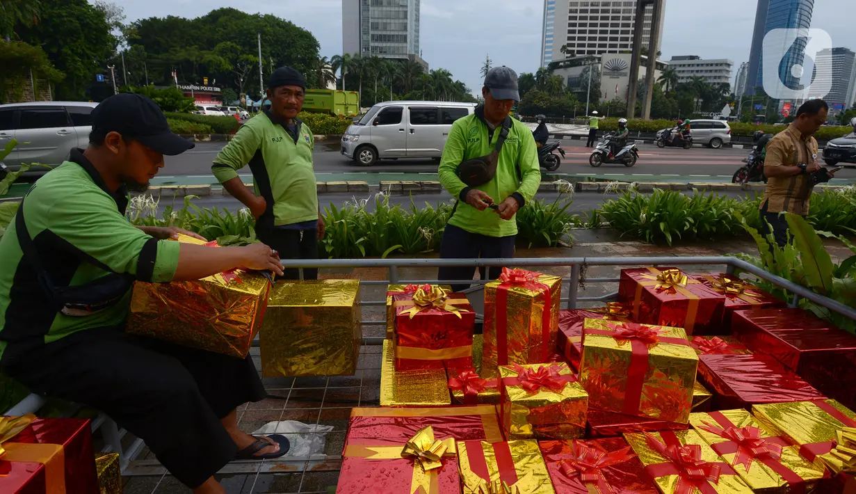 Petugas menghias kado Natal di Bundaran HI, Jakarta, Kamis (23/12/2021). Christmas Carol dilakukan di tujuh titik yang pada hari ini memasang pohon Natal di beberapa titik tersebut. (merdeka.com/Imam Buhori)