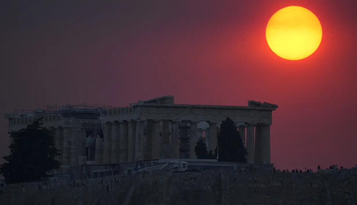 Asap dari kebakaran hutan di pinggiran ibu kota Yunani menutupi matahari saat terbenam di atas kuil Parthenon di atas Acropolis kuno di Athena, Selasa, 22 Agustus 2023. (AP Photo/Thanassis Stavrakis)