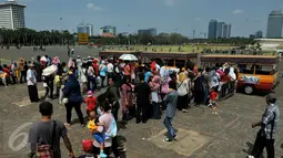 Warga antre untuk menaiki kereta wisata ketika berwisata di Monumen Nasional atau Monas, Jakarta, Minggu (19/7/2015). Ikon kota Jakarta tersebut menjadi tempat wisata alternatif warga saat liburan lebaran. (Liputan6.com/Johan Tallo)