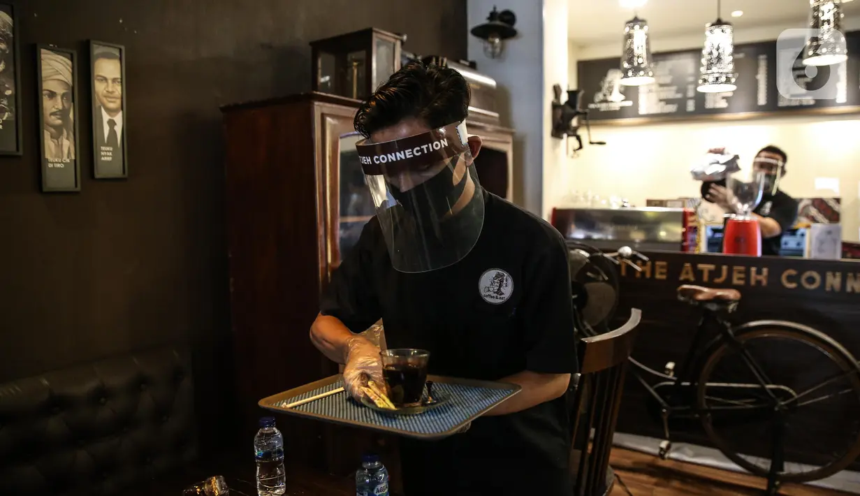 Pramusaji menggunakan pelindung wajah, masker dan sarung tangan saat melayani pelanggan di The Atjeh Connection Coffee and Resto, Jakarta, Senin (8/6/2020). Tempat ini siap menerapkan protokol kesehatan dalam menerapkan tatanan kehidupan baru atau ‘new normal’. (Liputan6.com/Faizal Fanani)