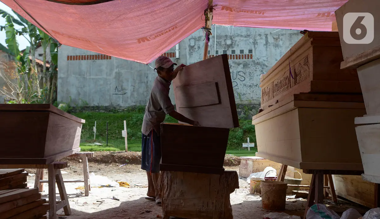 Herman pengrajin peti mati menyelesaikan pembuatan peti mati di Pondok Kelapa, Jakarta Timur, Rabu (6/5/2020). Di tengah pandemi COVID-19 pembuatan peti mengalami kenaikan sekitar 15-30 peti di bandingkan hari biasanya. (merdeka.com/Imam Buhori)