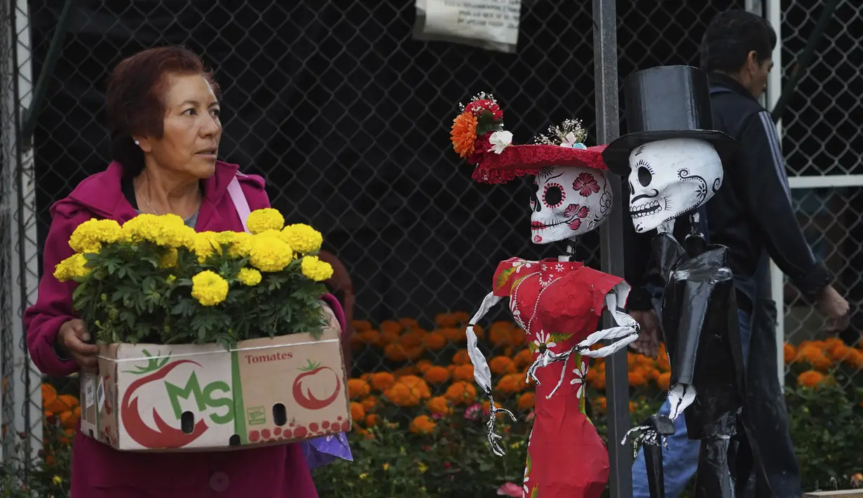 Seorang perempuan membawa bunga cempasuchil di pasar bunga di Acuexcomatl, Xochimilco, Mexico City, Rabu (19/10/2022). Pada peringatan Hari Orang Mati, karangan bunga besar disusun bersama potret orang-orang terkasih yang telah meninggal. (AP Photo/Marco Ugarte)