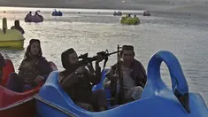 Sejumlah pasukan Taliban saat menaiki perahu kayuh di Danau Qargha di sebuah pekan raya di Kabul barat (28/9/2021). Sambil membawa senjata laras panjang sambil berjaga, mereka mengayuh perahu bebek memutari danau. (AFP/Wakil Kohsar)