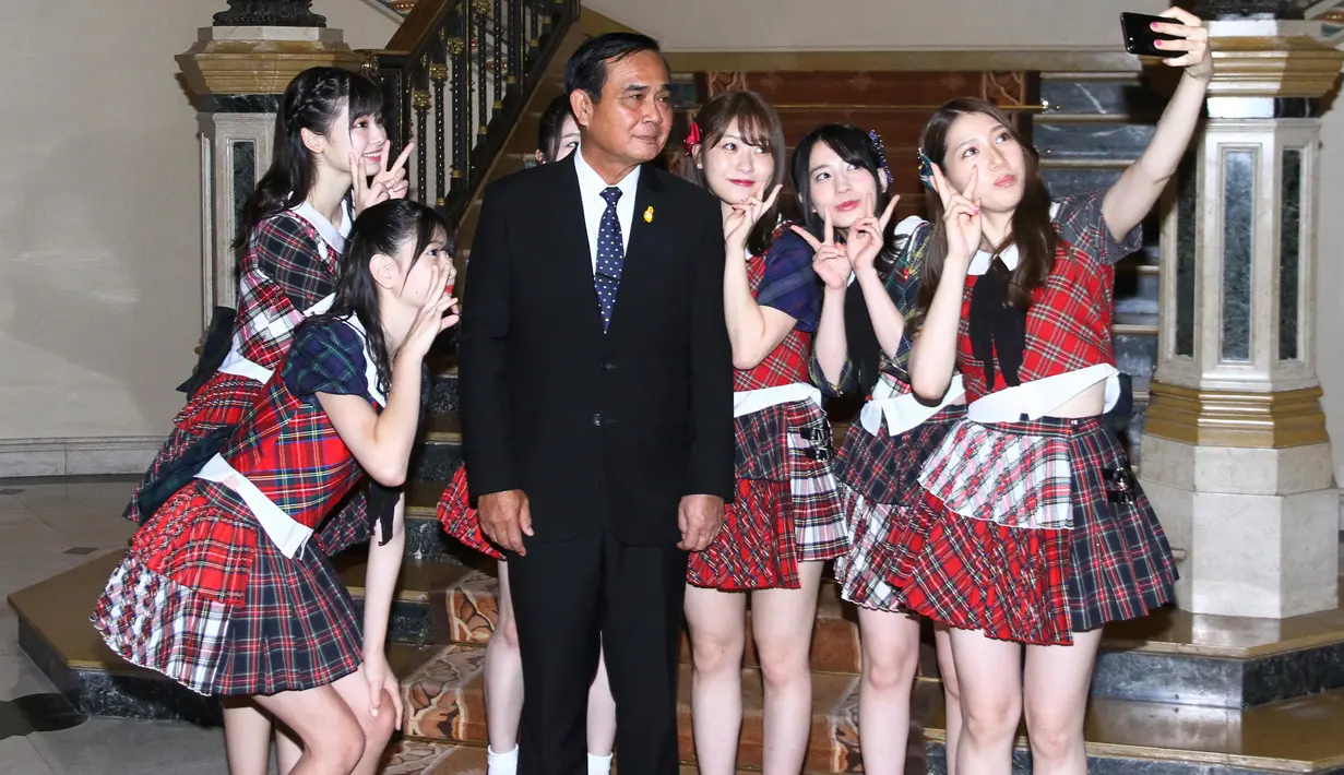 Grup musik Jepang, AKB48 berswafoto dengan PM Thailand, Prayut Chan-O-Cha di Bangkok, Kamis (13/8). Keenam member AKB48 menari di hadapan PM Thailand dengan lagu populer mereka "Koi Suru Fortune Cookie". (Government Spokesman Office via AP)