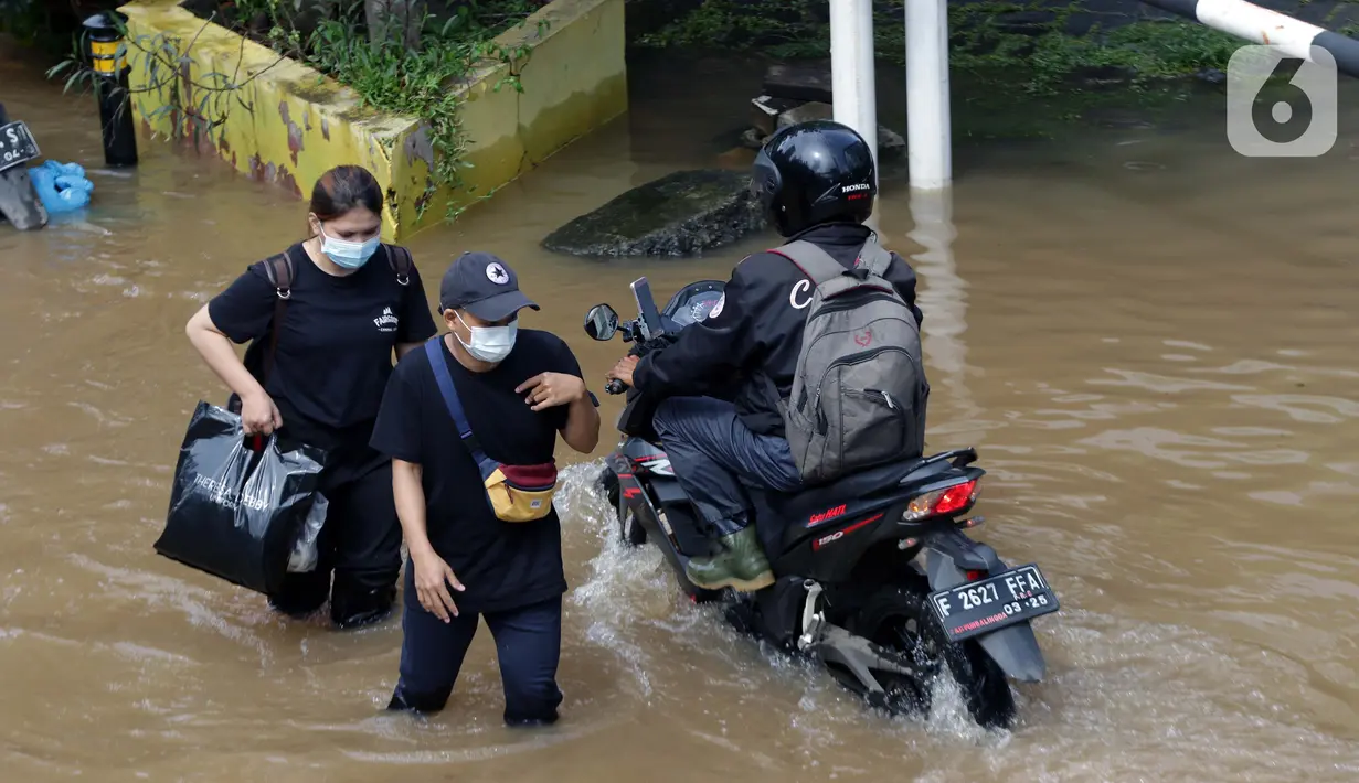 Warga berjalan menyusuri banjir yang menggenangi sebagian ruas Jalan Warung Buncit Raya, Jakarta, Sabtu (20/2/2021). Hujan yang mengguyur Jakarta sejak Jumat (19/2) membuat arus lalu lintas sejumlah jalan di Jakarta lumpuh akibat terendam banjir. (Liputan6.com/Helmi Fithriansyah)