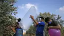 Sejumlah pria Palestina menyiapkan balon dengan alat peledak yang akan diterbangkan ke arah Israel di dekat kamp pengungsi al-Bureij, sepanjang perbatasan Israel- Jalur Gaza (12/8/2020). (AFP Photo/Mohammed Abed)