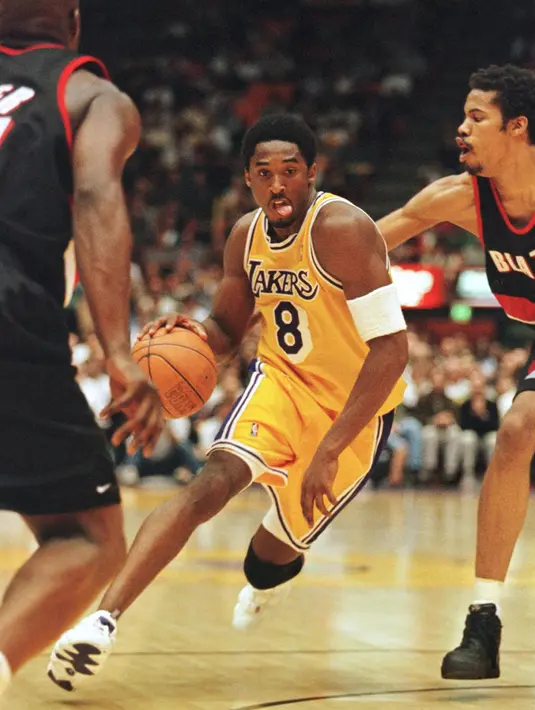 Pemain Los Angeles Lakers, Kobe Bryant membawa bola melewati pemain Portland Trailblazers Rasheed Wallace selama pertandingan playoff di Los Angeles pada 24 April 1998. Bryant meninggal bersama putrinya yang berusia 13 tahun Gianna dalam kecelakaan helikopter di Calabasas. (AFP Photo/Vince Bucci)