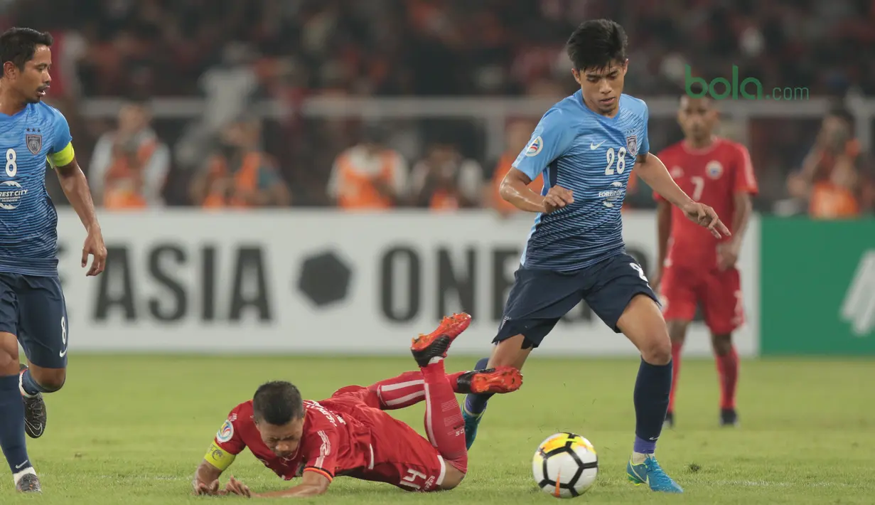 Pemain Persija Jakarta, Ismed Sofyan jatuh saat berebut bola dengan dua pemain JDT pada laga Piala AFC 2018 di Stadion Utama Gelora Bung Karno, Jakarta, Selasa (10/4/2018). Persija Jakarta menang 4-0.  (Bola.com/Nick Hanoatubun)