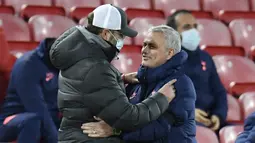 Manajer Liverpool, Jurgen Klopp (kiri) memeluk manajer Tottenham Hotspur, Jose Mourinho, sebelum dimulainya laga lanjutan Liga Inggris 2020/21 pekan ke-13 di Anfield Stadium, Rabu (16/12/2020). Liverpool menang 2-1 atas Tottenham. (AFP/Peter Powell/Pool)