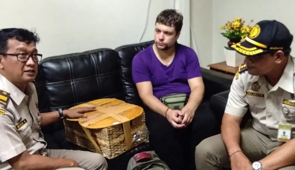 Petugas BKSD Bali menunjukkan pelaku warga negara Rusia Andrei Zhestkov (tengah) yang menyelundupkan orangutan berusia dua tahun di keranjang rotan, di bandara internasional Bali (23/3). Orang utan itu rencananya akan dibawa dari Bali ke Rusia. (AFP Photo/Badan Konservasi Sumber Daya Alam Bali)