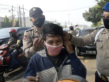 Anggota polisi dari Polsek Parung membantu memasangkan masker kepada pengendara sepeda motor di depan Polsek Parung, Kabupaten Bogor, Jawa Barat, Rabu (2/9/2020). Pembagian masker gratis setiap usai apel ini inisiatif anggota sejak masa pandemi COVID-19. (merdeka.com/Dwi Narwoko)