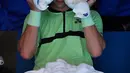 Petenis Lithuania Ricardas Berankis menggunakan handuk es saat istirahat saat bermain melawan Swiss Stan Wawrinka dalam pertandingan putaran pertama Australia Terbuka di Melbourne, Australia, (16/1). (AP Photo / Andy Brownbill)