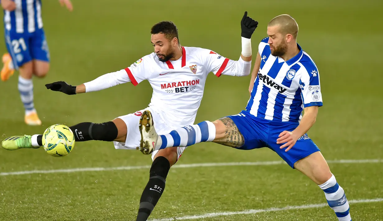 Penyerang Sevilla, Youssef En-Nesyri, berebut bola dengan bek Alaves, Victor Laguardia Cisneros, pada laga lanjutan Liga Spanyol di Stadion Mendizorrotza, Rabu (20/1/2021) dini hari WIB. Sevilla menang 2-1 atas Alaves. (AFP/Ander Gillenea)