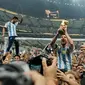Pemain Argentina Lionel Messi mengangkat trofi juara di depan para penggemar usai mengalahkan Prancis pada pertandingan sepak bola final Piala Dunia 2022 di Stadion Lusail, Lusail, Qatar, 18 Desember 2022. Argentina menang 4-2 dalam adu penalti setelah pertandingan berakhir imbang 3 -3. (AP Photo/Martin Meissner)