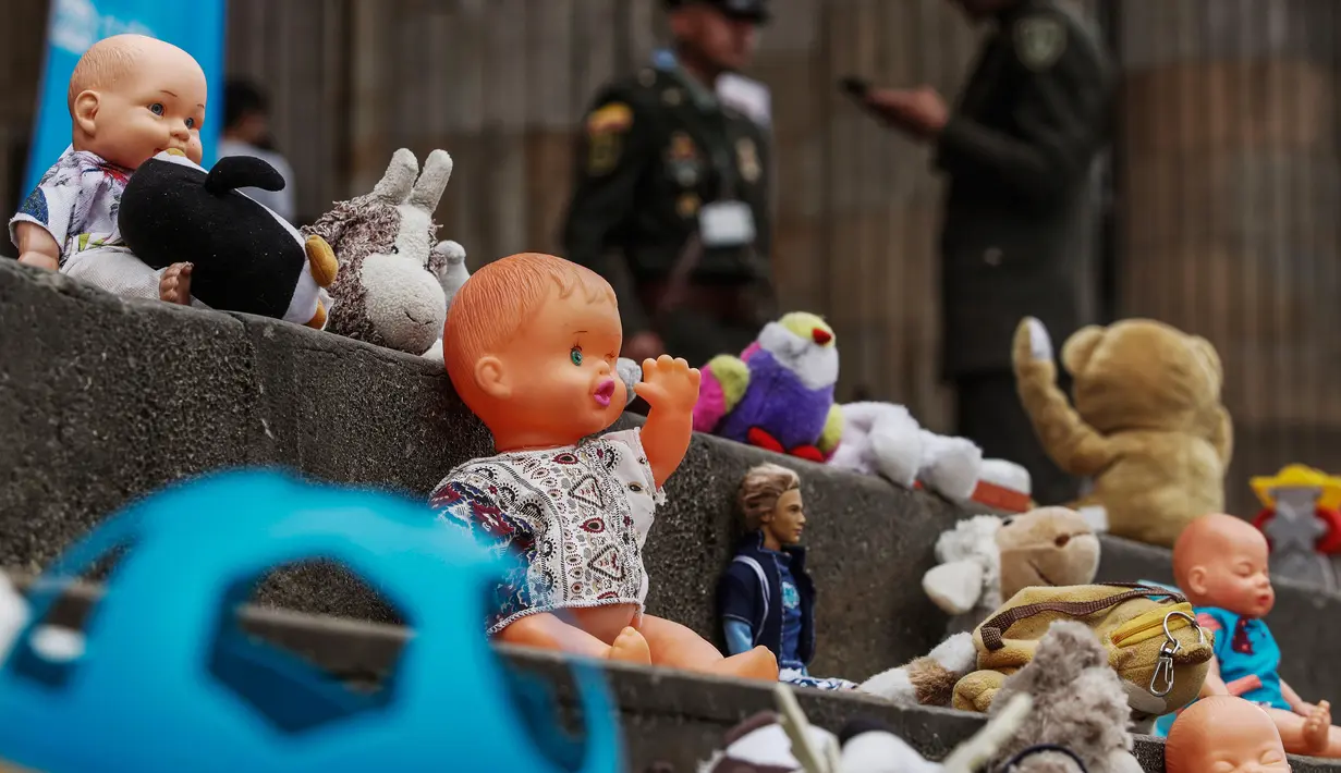 Boneka mainan diletakkan di halaman gedung Kongres Kolombia untuk memprotes kekerasan seksual terhadap anak-anak di Bogota, Selasa (20/11). Protes bertujuan untuk meningkatkan kesadaran tentang tanggung jawab perlindungan anak-anak. (DANIEL MUNOZ/AFP)