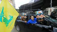 Warga Lebanon mengangkat potret pemimpin Hizbullah yang terbunuh, Hassan Nasrallah dan Hashem Safieddine, bersama dengan bendera kuning kelompok militan tersebut saat orang-orang kembali ke pinggiran selatan Beirut akibat gencatan senjata. (AFP)