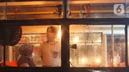 Pegawai melayani pembeli di kafe yang menggunakan angkutan metromini di Bekasi, Jawa Barat, Kamis (15/4/2021). Kafe ini berinovasi di tengah pandemi COVID-19 dengan menggunakan armada metromini yang sudah tidak terpakai sebagai tempat makan pengunjung. (Liputan6.com/Herman Zakharia)