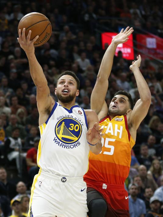 Aksi pemain Warriors, Stephen Curry (30) melakukan lays up melewati adangan peemain Utah Jazz, Raul Neto pada lanjutan NBA basketball game di Vivint Smart Home Arena, Salt Lake City, (30/1/2018). Utah menang 129-99. (AP/Rick Bowmer)