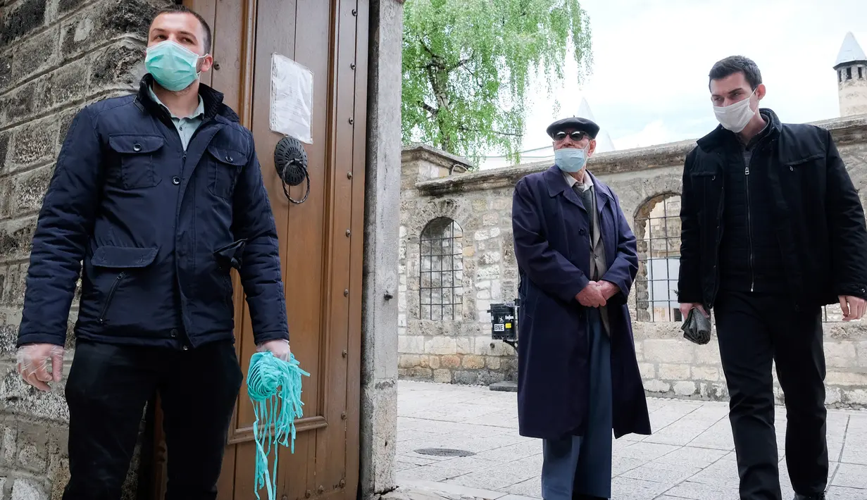 Pengurus memegang masker di luar masjid Begova di Sarajevo, Rabu (6/5/2020). Setelah hampir dua bulan dikurung, Bosnia membuka kembali masjid-masjid untuk Umat Muslim yang merayakan bulan suci Ramadan dengan tetap mematuhi aturan jarak sosial dan menggunakan peralatan pelindung. (AP/Kemal Softic)