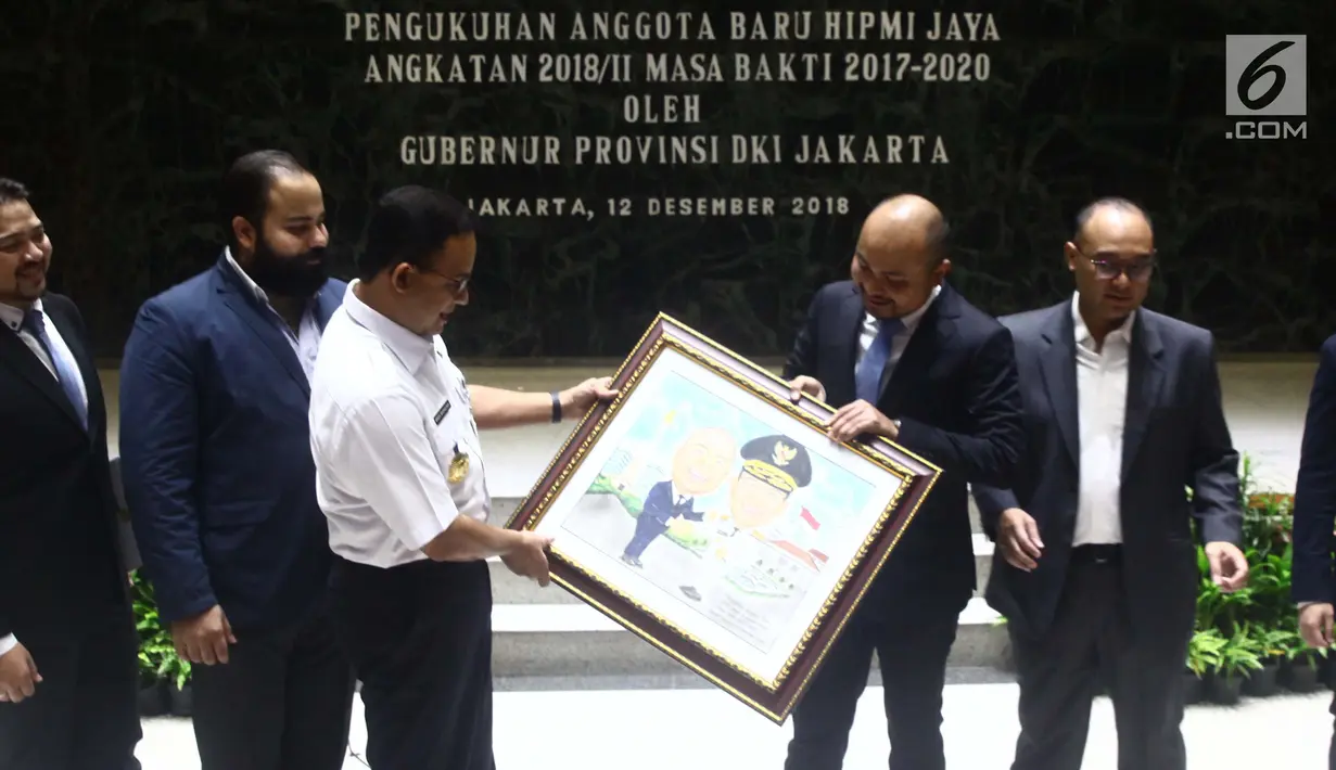 Ketua Umum HIIPMI Jaya Afifuddin Suhaeli Kalla (kanan) menyerahkan cendera mata kepada Gubernur DKI Jakarta Anies Baswedan (kiri) saat pelantikan anggota HIPMI Jaya di Balai Kota Jakarta, Rabu (12/12). (Liputan6.com/Angga Yuniar)