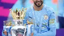 Gelandang Manchester City, Riyad Mahrez berpose dengan trofi Liga Inggris saat merayakan timnya meraih juara usai mengalahkan Everton di stadion Etihad di Manchester, Minggu (23/5/2021). (AFP Photo/Pool/Dave Thompson)