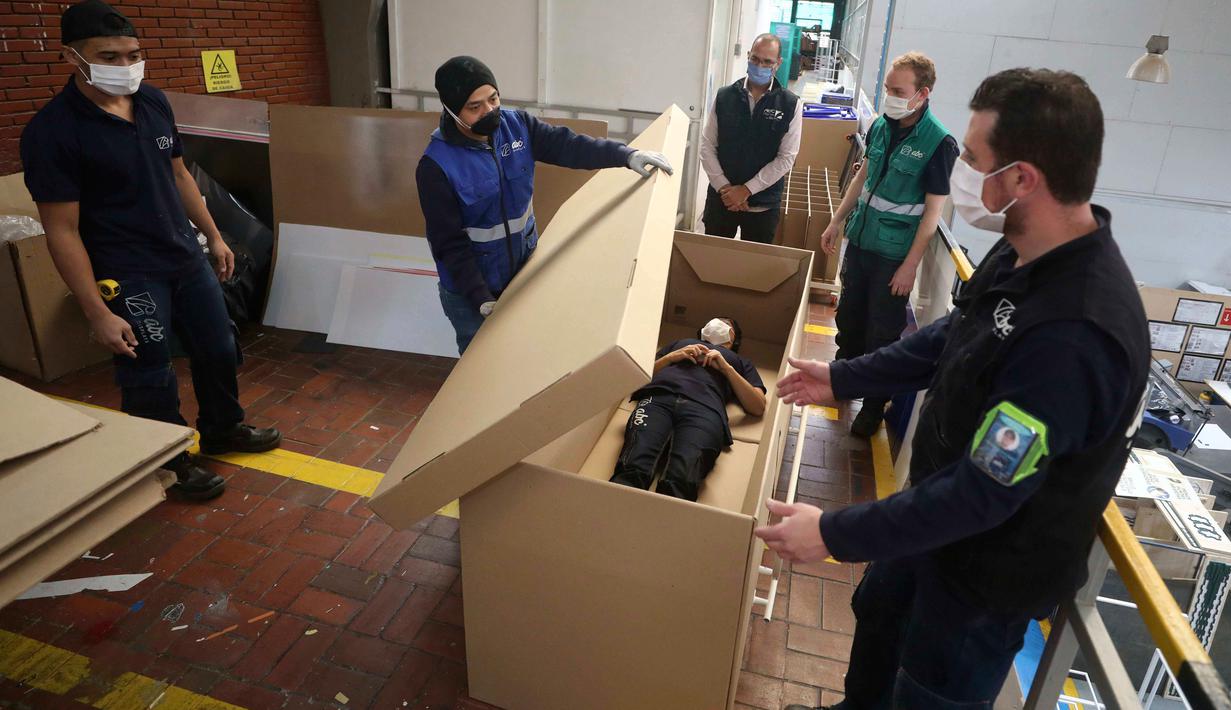 Rodolfo Gomez dan karyawannya mendemonstrasikan desain kardus mereka dapat berfungsi sebagai tempat tidur rumah sakit dan peti mati untuk pasien COVID-19 di Bogota, Kolombia, Jumat (8/5/2020). Perusahaan ini menanggapi kekurangan tempat tidur dan peti mati selama pandemi.  (AP/Fernando Vergara)