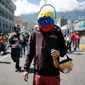 Seorang pengunjuk rasa memakai topeng berwarna bendera Venezuela, saat ikut serta dalam demonstrasi anti-pemerintah ke Mahkamah Agung di Caracas, Venezuela, Kamis, 6 Juli 2017. (AP Photo / Ariana Cubillos)